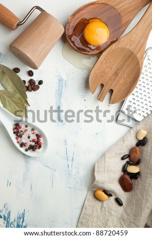 Kitchen background with kitchen utensil, broken egg, salt and pepper on white wooden table