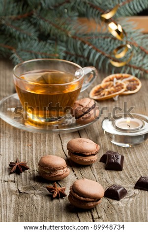 Chocolate macaroons with pieces of white and black chocolate and cup of hot tea on old wooden table
