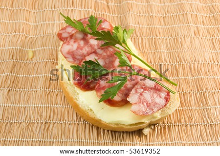 image of a sandwich with sausage and a sprig of parsley on the jute napkin