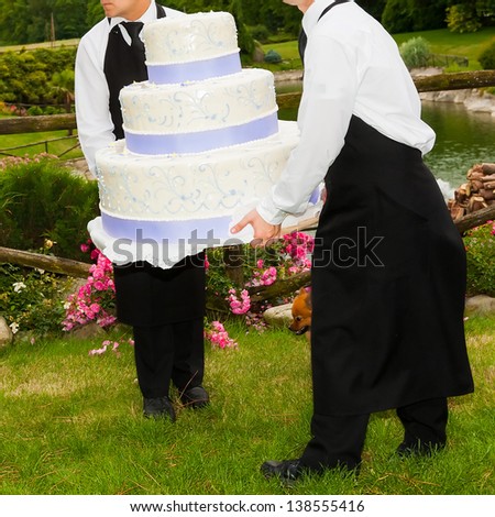 waiters carry the wedding cake