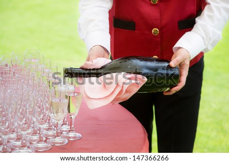 waiter pouring champagne into a flute