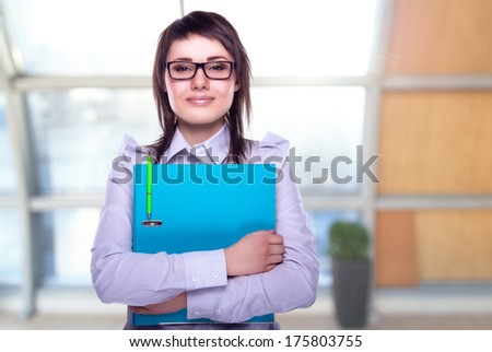 Beautiful business woman with a folder in hands. Business decisions. Office workers. Friendly smiling girl. Beautiful light background.