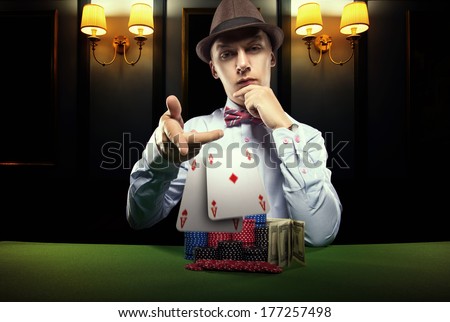 Beautiful young man on a beautiful background playing poker. Good luck in card games on the big money.