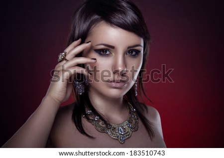 Beautiful girl with a necklace and a ring on red background. Gold Jewelry
