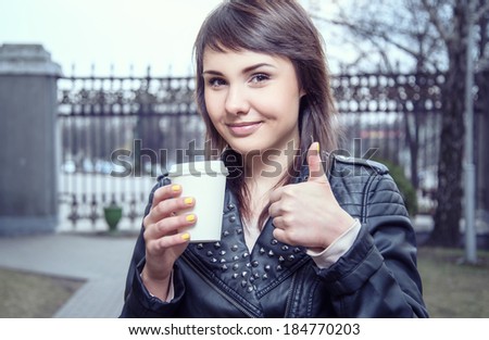 Beautiful young woman is drinking coffee outdoors. Invigorating morning. Stylish look