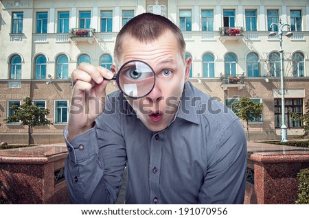 Young funny guy looking through magnifier