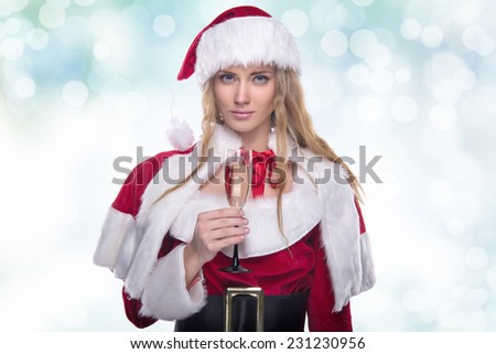 Beautiful young girl in a Christmas costume. New Year\'s holidays. Woman celebrating Christmas. Girl with a glass of champagne