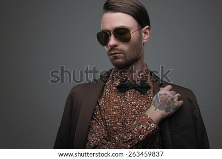 Handsome stylish young man. Brutal man with a beard and sunglasses with bow-tie