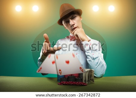 Beautiful young man on a beautiful background playing poker. Good luck in card games on the big money. Looking at the camera