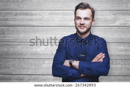 Handsome stylish young man in shirt looking at the camera. Office worker. Business decisions. Wood background
