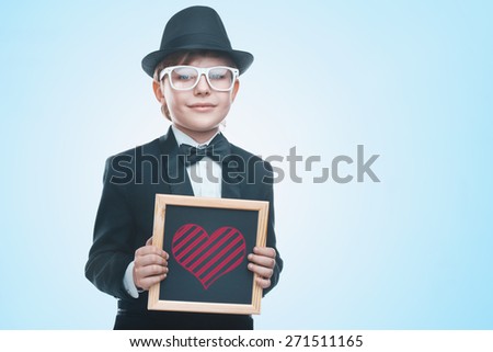 Beautiful little boy with a board. Looking at the camera. Drawing a heart. Valentine's day holiday