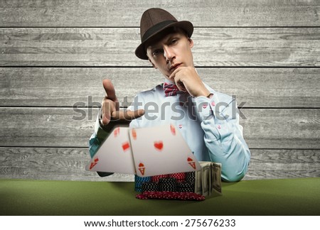 Beautiful young man on a beautiful background playing poker. Good luck in card games on the big money. Looking at the camera