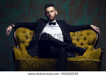 Stylish young man in a suit and bow tie. Business style. Fashionable image. Evening dress. Sexy man standing and looking at the camera. Fashion look