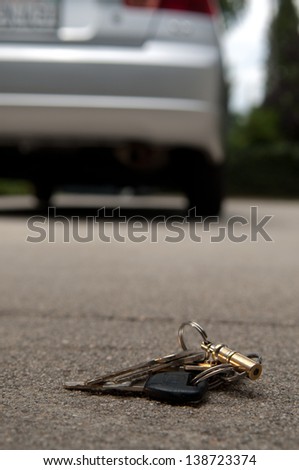 Lost keys dropped on the ground behind a car, forgotten by owner