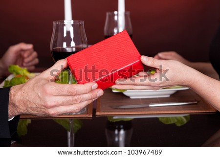 Man giving present to a woman at romantic dinner in restaurant