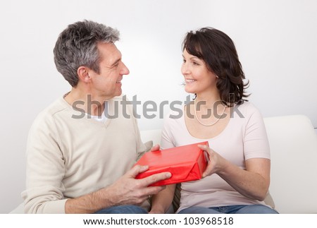 Mature man giving a present to his woman at home