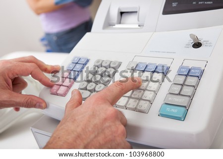 Sales person entering amount on cash register in retail store