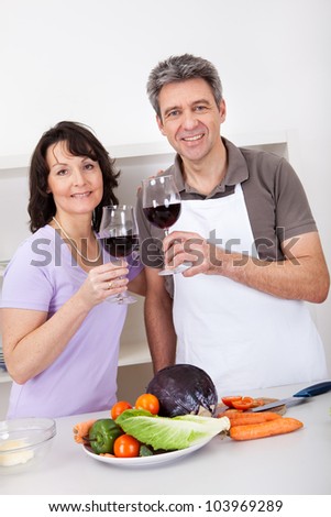 Senior couple cooking at home and drinking wine. Isolated on white