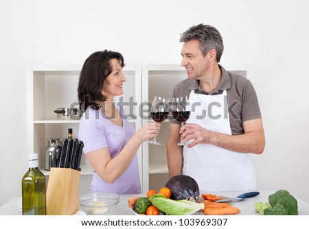 Senior couple cooking at home and drinking wine. Isolated on white