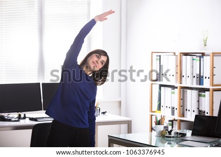 Young Businesswoman Doing Stretching Exercise In Office