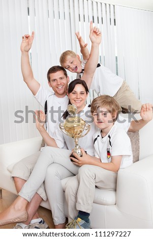 Young family watching football match at home