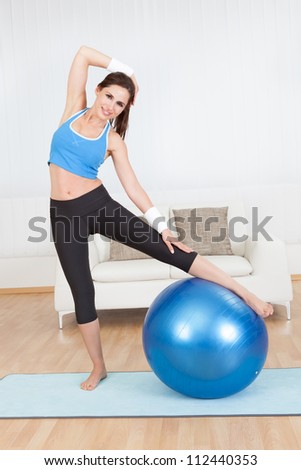 Young woman stretching her muscles at home
