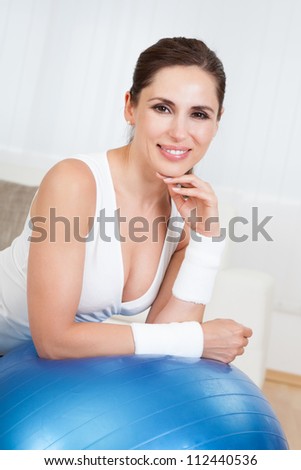 Close up of a happy smiling woman with a large blue pilates ball in a health and fitness concept