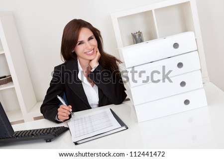Portrait of a businesswoman with lots of paperwork at office desk