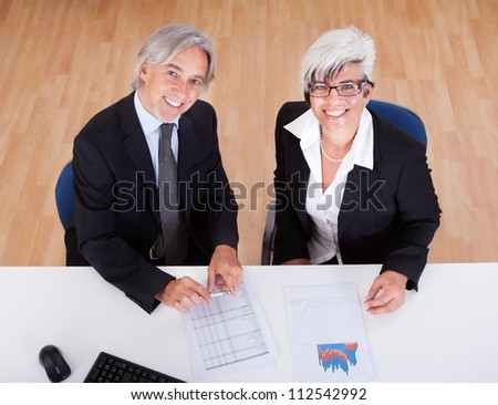 Smiling senior partners sitting together at a desk having a business meeting