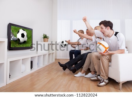 Jubilant family watching television as they cheer on their home side in a sporting competition