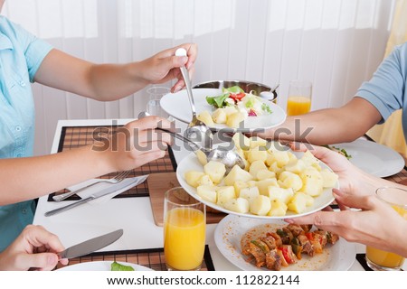 Young happy family with teenage children sitting down to eat a cold lunch of meat and salads