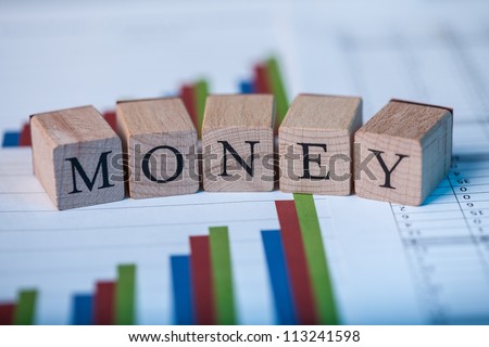 Wooden blocks with the lettering Money on top of ascending bar graphs analyzing the statics and performance of shares within the market