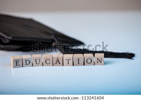 Education concept with the alphabet letters for Education spelt out on wooden blocks beside a graduation cap