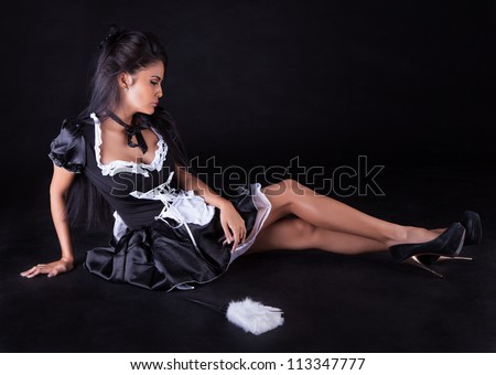 Beautiful seductive woman posing sitting on the floor in a cute little maids outfit with miniskirt