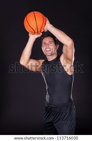 Young Man Throwing Basketball Isolated On Black Background