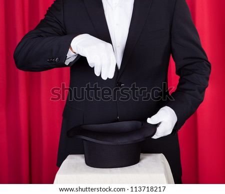 A Magician In A Black Suit Holding An Empty Top Hat And Magic Wand