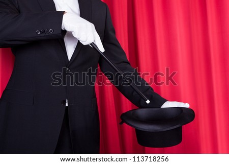A Magician In A Black Suit Holding An Empty Top Hat And Magic Wand