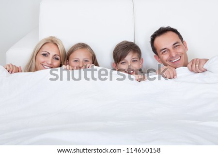 Happy Family With Two Children In Bed Under Cover, Indoors