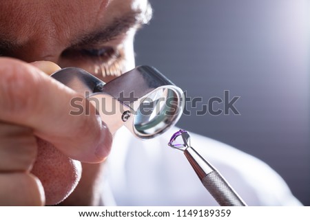 Close-up Of A Male Jeweler\'s Hand Looking At Diamond Through Magnifying Loupe