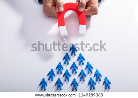 Businessman\'s Hand Attracting Blue Team With Horseshoe Magnet On White Background