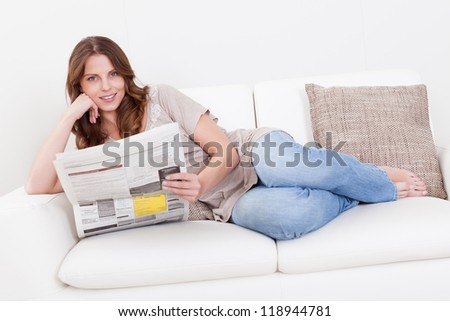 Woman reading the newspaper while drinking a refreshing cup of morning coffee