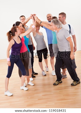 Group of athletic healthy adults in gym giving group high five