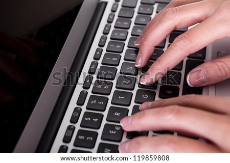 High angle cropped view image of female hands typing on a laptop keyboard with a blank white screen