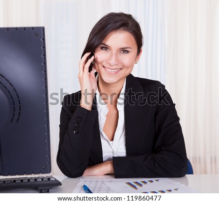 Happy brunette business woman listening to someone on her mobile phone