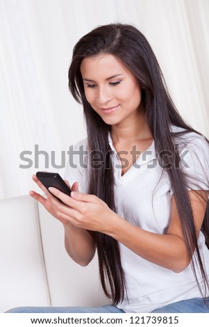 Attractive woman with long straight brunette hair smiling at the camera and talking on her mobile phone