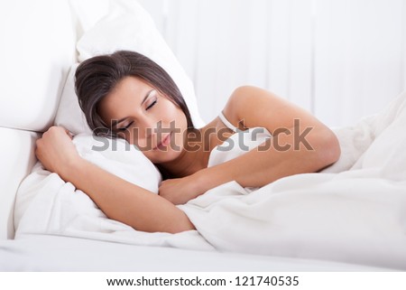 Closeup portrait of a beautiful young woman sleeping peacefully in her bed facing the camera