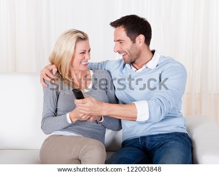 Young couple fighting for TV remote at home