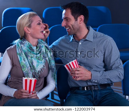 Loving couple sharing their popcorn while seated at the cinema watching movies