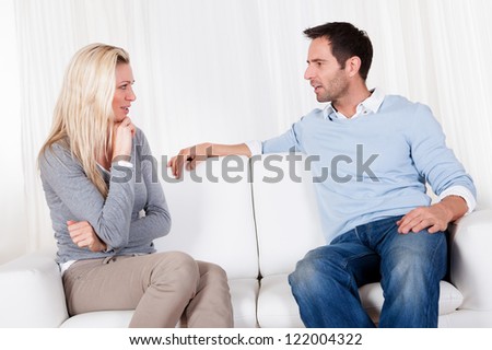 Couple who have fallen out over a disagreement sitting on a sofa