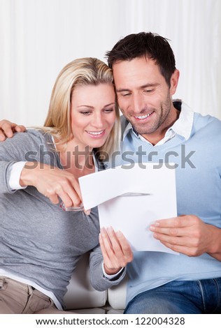 Laughing woman about to cut up a document poised with the scissors at the ready while being watched by her husband